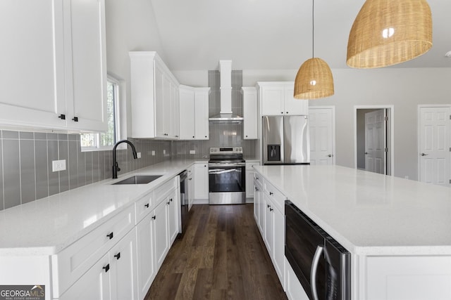 kitchen with pendant lighting, sink, a center island, stainless steel appliances, and wall chimney range hood