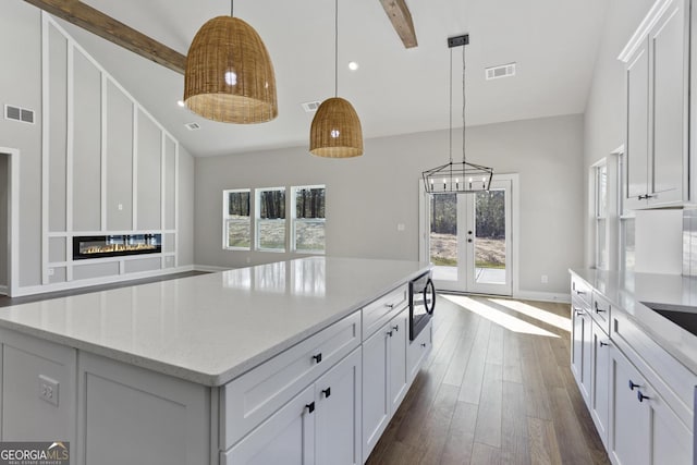 kitchen featuring hanging light fixtures, dark wood-type flooring, a center island, and white cabinets