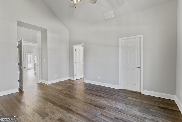 empty room featuring dark wood-type flooring and high vaulted ceiling