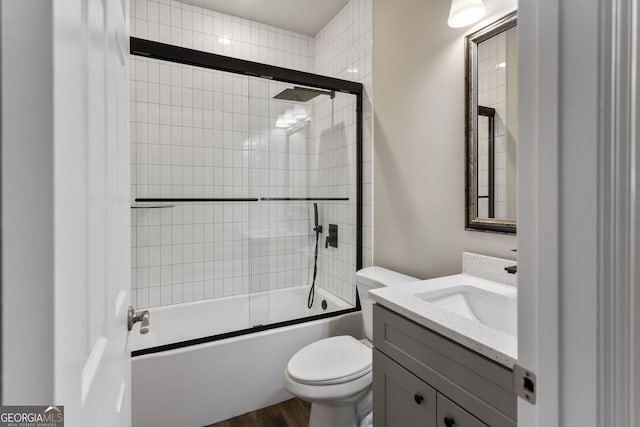 full bathroom with bath / shower combo with glass door, vanity, toilet, and hardwood / wood-style flooring