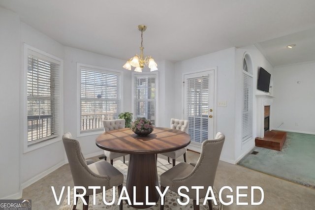 dining space featuring baseboards, a wealth of natural light, a chandelier, and a fireplace