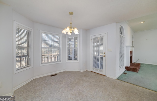 unfurnished dining area with carpet flooring, visible vents, baseboards, a fireplace, and a notable chandelier
