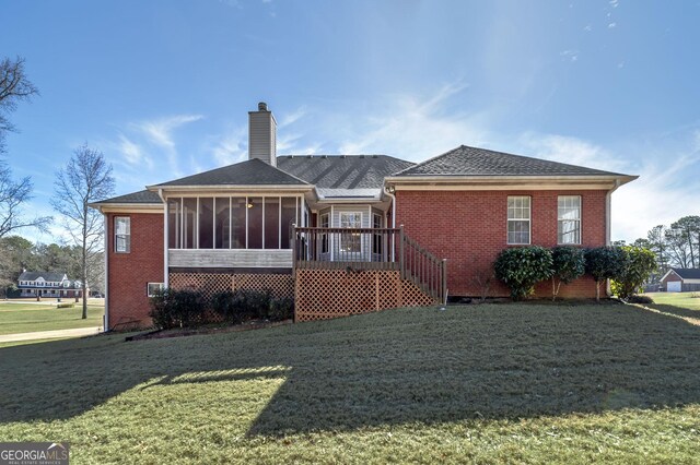 rear view of house featuring a sunroom, brick siding, a yard, a chimney, and roof with shingles
