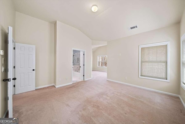 carpeted empty room with vaulted ceiling