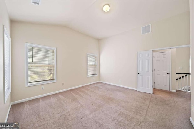 unfurnished room with lofted ceiling and light carpet