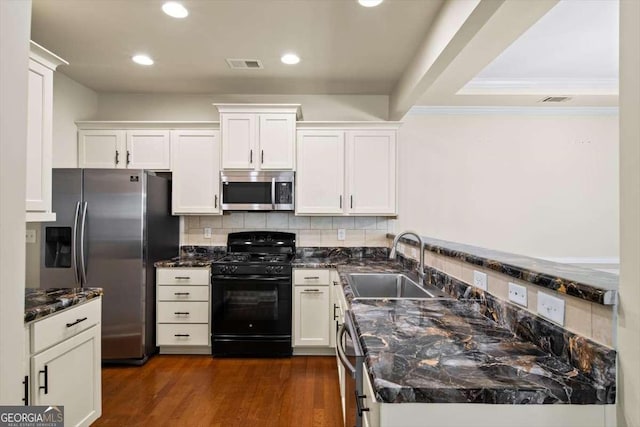 kitchen with white cabinetry, sink, dark stone countertops, dark hardwood / wood-style flooring, and stainless steel appliances