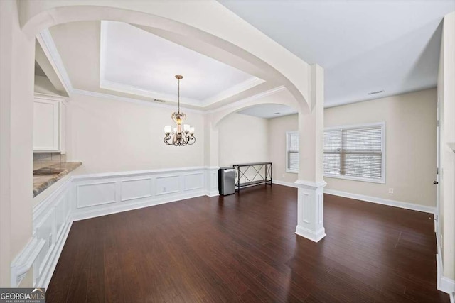 unfurnished dining area with ornamental molding, a tray ceiling, and dark hardwood / wood-style flooring