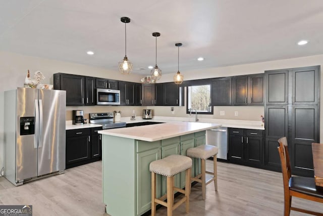 kitchen featuring a kitchen island, a kitchen breakfast bar, hanging light fixtures, light hardwood / wood-style floors, and stainless steel appliances