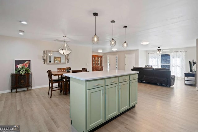 kitchen with hanging light fixtures, a kitchen island, green cabinets, and light wood-type flooring