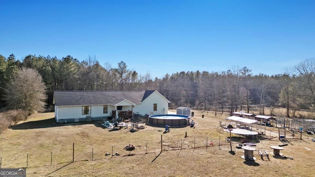 back of property with a fenced in pool and a yard