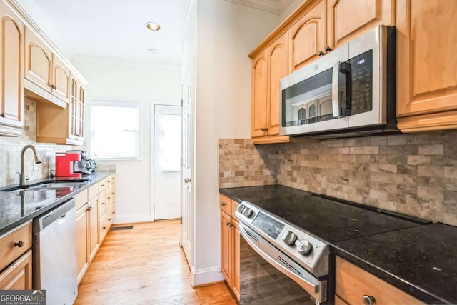 kitchen with dark stone countertops, sink, crown molding, and appliances with stainless steel finishes