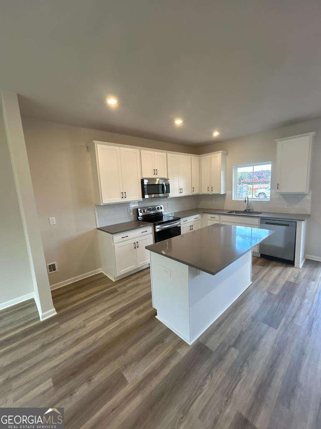 kitchen with white cabinetry, tasteful backsplash, a center island, appliances with stainless steel finishes, and dark hardwood / wood-style floors