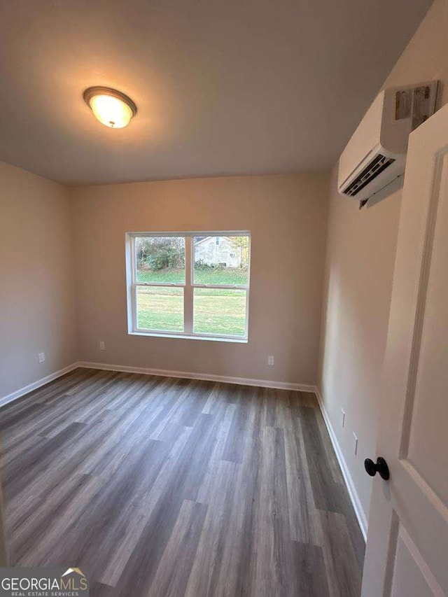 empty room featuring dark wood-type flooring and a wall mounted air conditioner