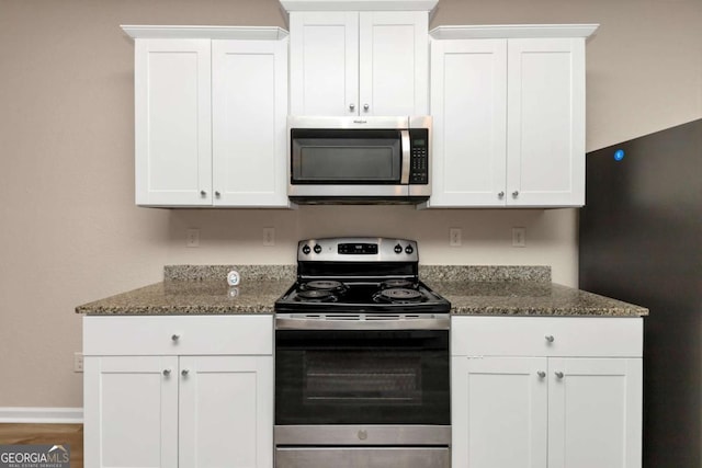 kitchen featuring stainless steel appliances, dark stone countertops, and white cabinets