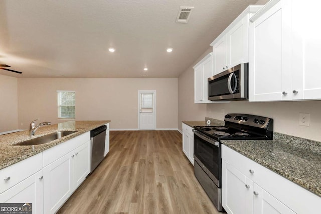 kitchen with sink, white cabinetry, stone countertops, light wood-type flooring, and stainless steel appliances