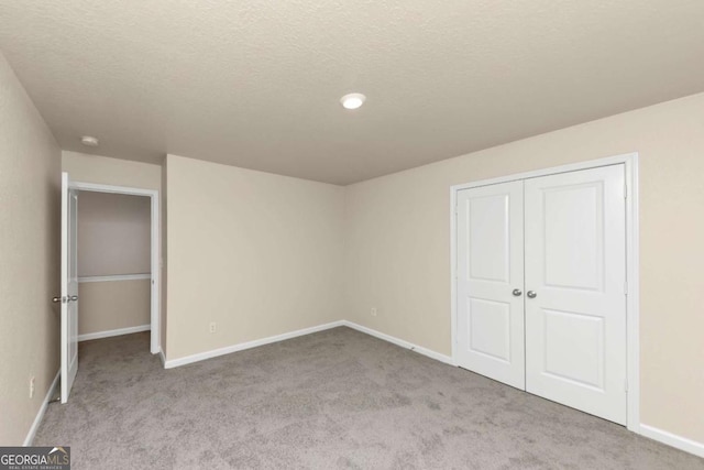 unfurnished bedroom featuring light carpet, a closet, and a textured ceiling