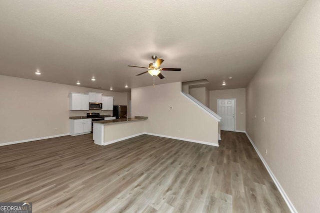 unfurnished living room featuring ceiling fan, a textured ceiling, and light hardwood / wood-style floors