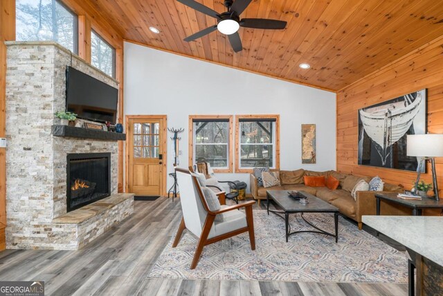 living room with hardwood / wood-style floors, high vaulted ceiling, a fireplace, ceiling fan, and wood ceiling