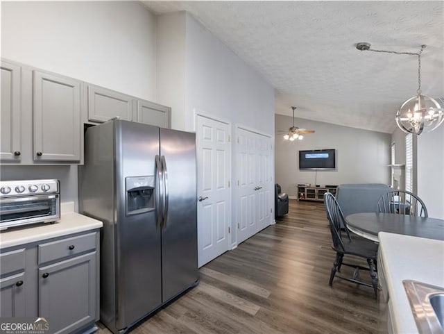 kitchen with stainless steel fridge, gray cabinets, hanging light fixtures, dark hardwood / wood-style floors, and vaulted ceiling