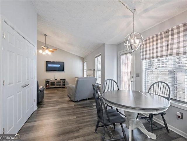 dining room featuring ceiling fan with notable chandelier, dark hardwood / wood-style flooring, vaulted ceiling, and a textured ceiling