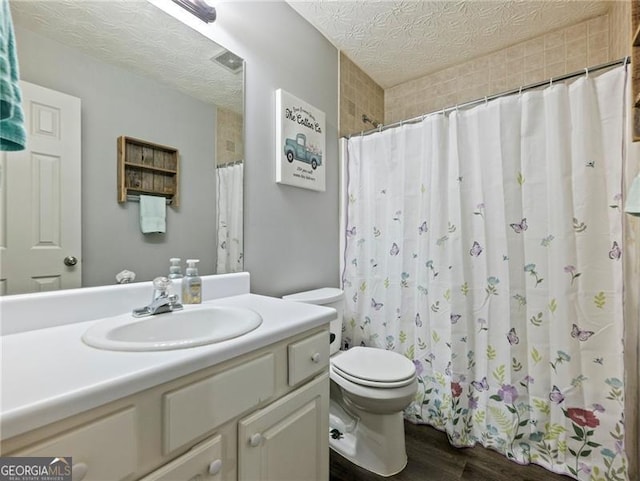 bathroom with hardwood / wood-style flooring, vanity, a textured ceiling, and toilet