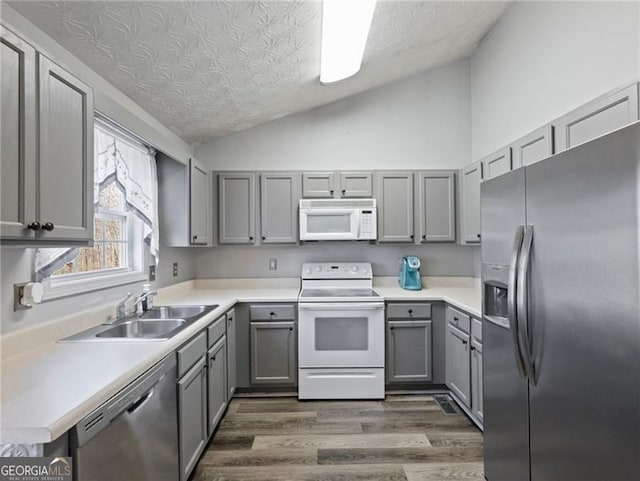 kitchen featuring dark wood-type flooring, sink, vaulted ceiling, a textured ceiling, and stainless steel appliances