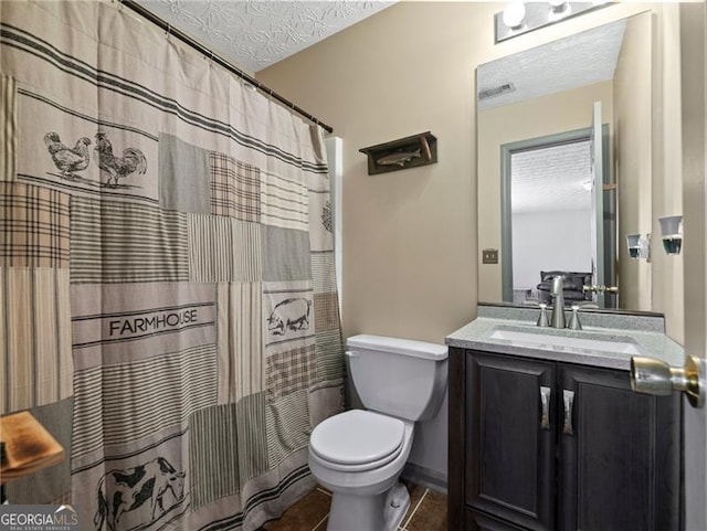 bathroom with tile patterned floors, vanity, toilet, and a textured ceiling