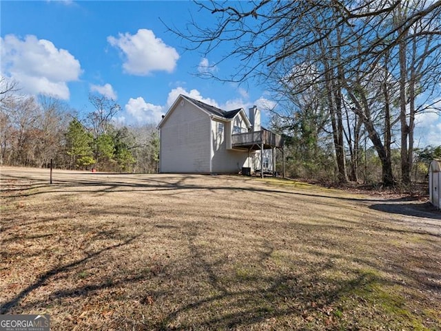 view of side of home with a deck and a lawn