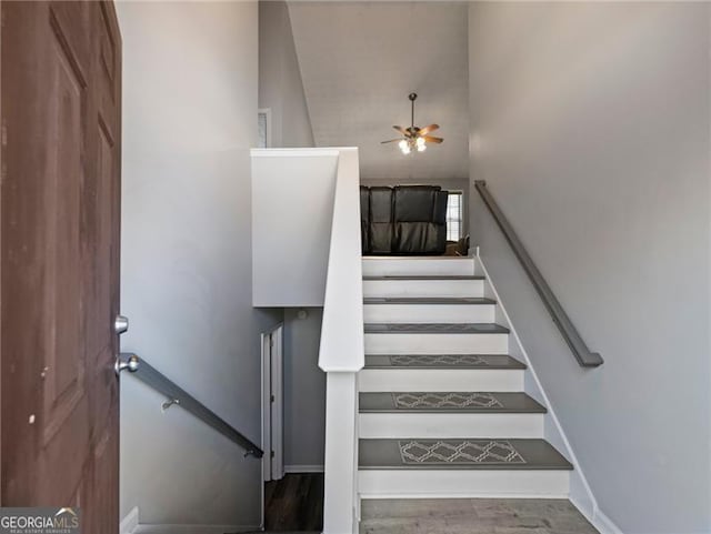 stairs featuring wood-type flooring and ceiling fan