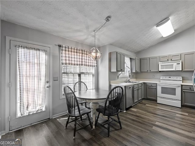 dining area featuring an inviting chandelier, lofted ceiling, sink, dark wood-type flooring, and a textured ceiling