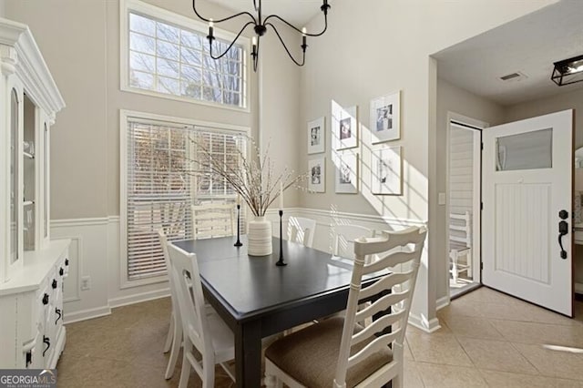 dining room featuring an inviting chandelier, light tile patterned floors, and a high ceiling