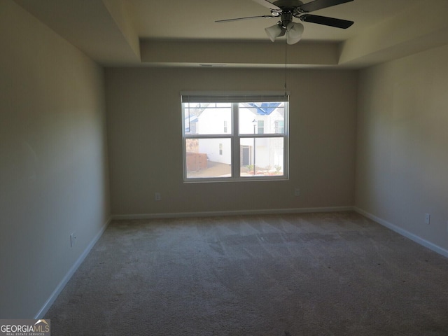 carpeted spare room featuring ceiling fan and a tray ceiling