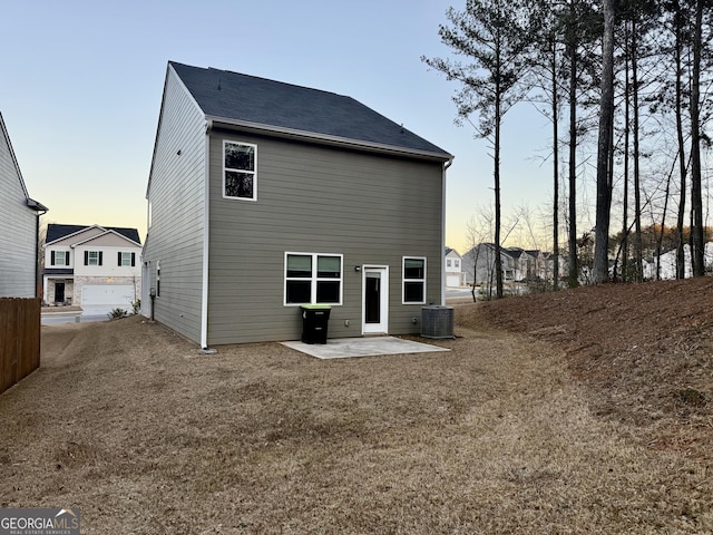 back house at dusk with a patio and central AC