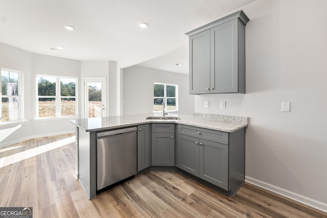 kitchen featuring sink, gray cabinetry, stainless steel dishwasher, kitchen peninsula, and light stone countertops