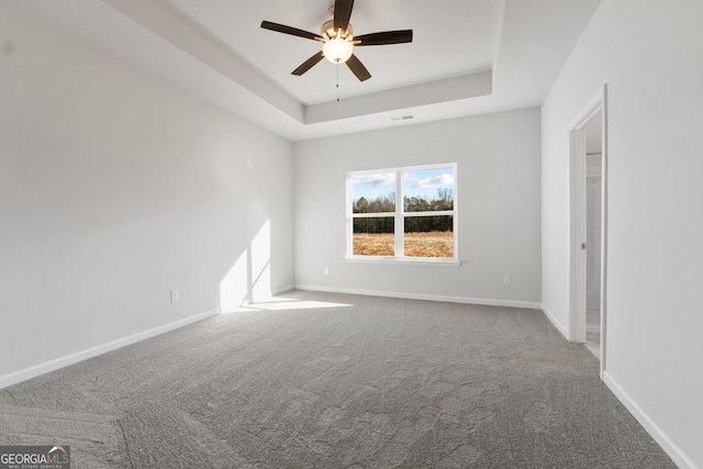 carpeted empty room featuring ceiling fan and a tray ceiling