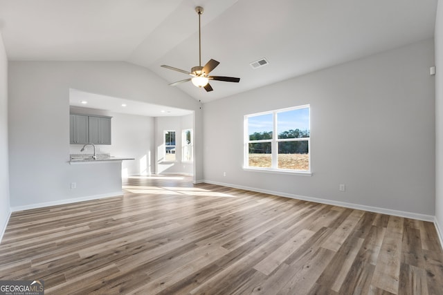 unfurnished living room with hardwood / wood-style flooring, high vaulted ceiling, sink, and ceiling fan