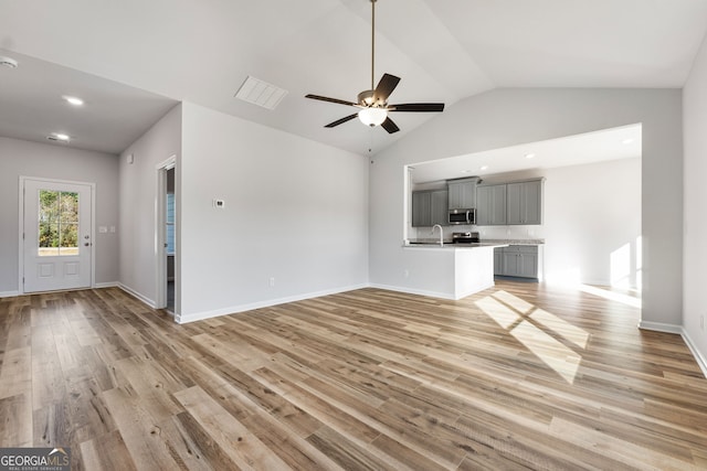 unfurnished living room featuring ceiling fan, lofted ceiling, sink, and light wood-type flooring