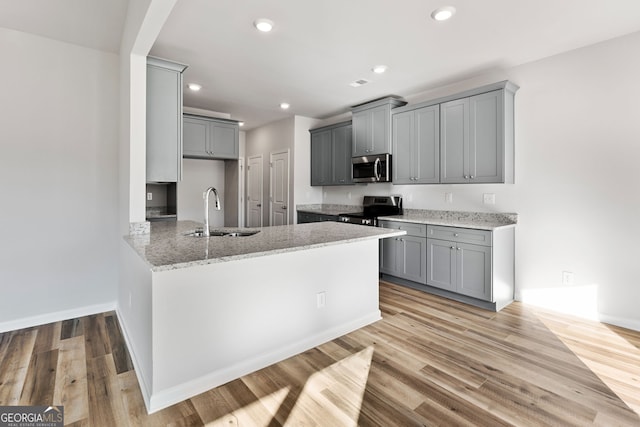 kitchen with appliances with stainless steel finishes, light hardwood / wood-style floors, sink, and gray cabinetry