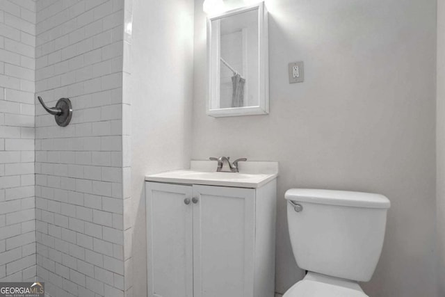 bathroom with vanity, toilet, and tiled shower