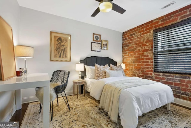 bedroom featuring hardwood / wood-style flooring, ceiling fan, and brick wall