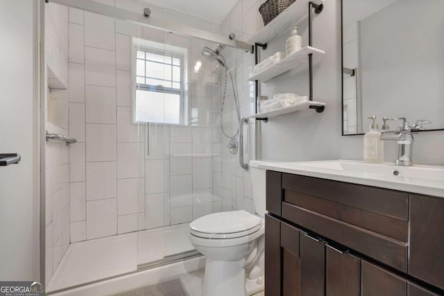 bathroom with vanity, a shower with shower door, and toilet