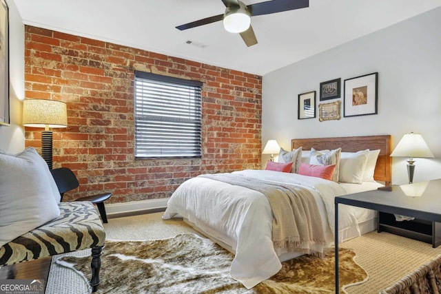 bedroom with ceiling fan and brick wall