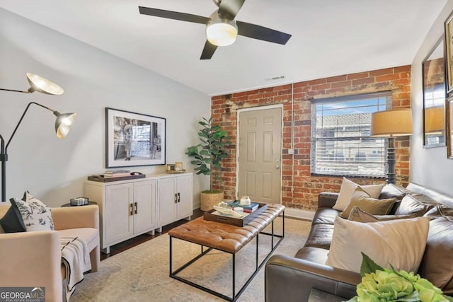 living room featuring ceiling fan, brick wall, and hardwood / wood-style floors