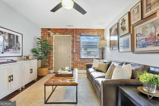 living room with ceiling fan, brick wall, and light hardwood / wood-style flooring