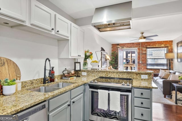 kitchen featuring sink, exhaust hood, kitchen peninsula, stainless steel appliances, and white cabinets