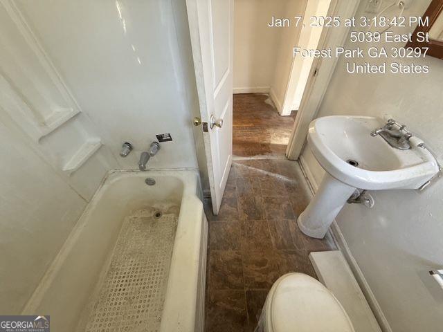 bathroom featuring sink, a tub, and toilet