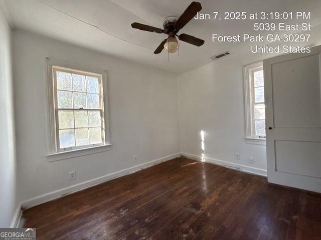 empty room with dark wood-type flooring and ceiling fan