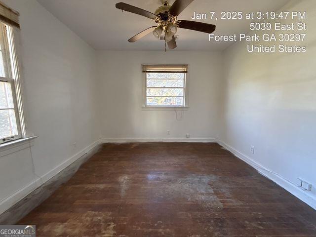 empty room featuring dark wood-type flooring and ceiling fan