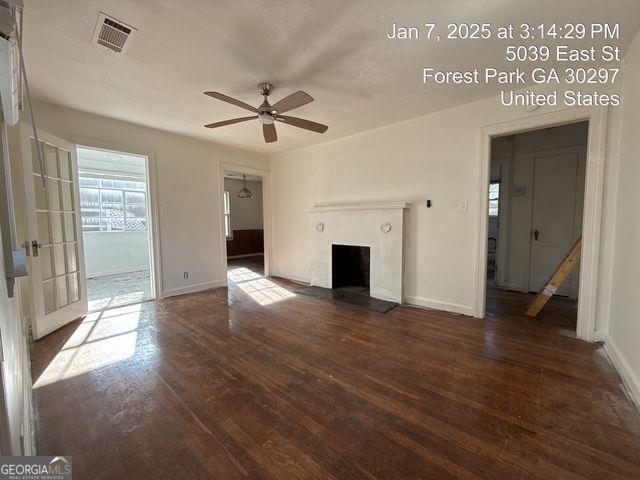 unfurnished living room featuring ceiling fan and dark hardwood / wood-style flooring