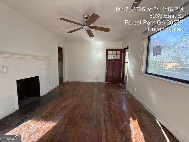 unfurnished living room featuring ceiling fan and dark hardwood / wood-style floors